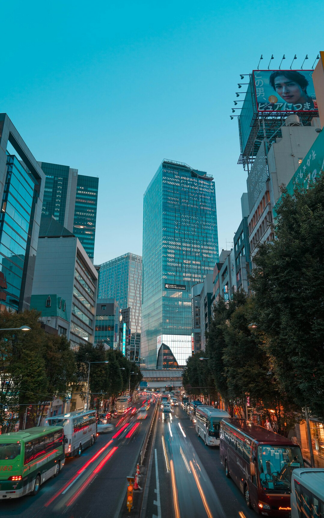 City street at dusk with glass buildings and light trails